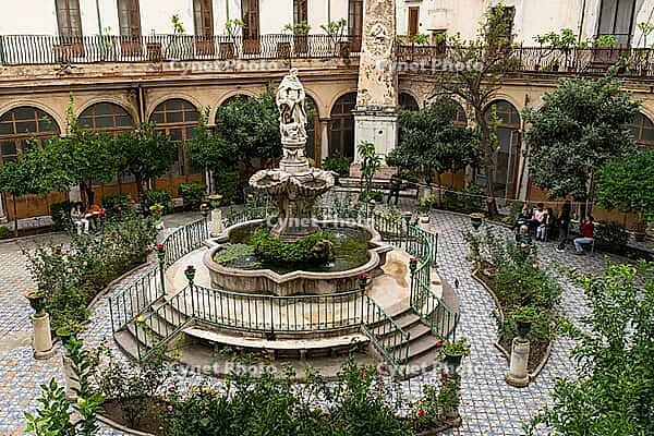 Palermo, Italy - 06.11.2022: Chiostro con fontana di San Domenico. Historic courtyard with ornate fountain and lush garden in a classical setting [IBR123646544]
