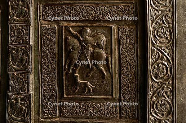 Monreale, Italy - 04.11.2022: Medieval knightly scene with intricate carved patterns on historical door [IBR123646555]