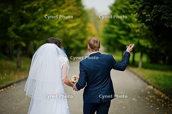 Wedding couple walking at green park [IBR123675069]
