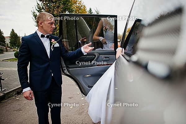 The groom takes the bride hand in the car [IBR123675082]