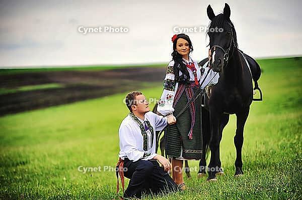 Young couple on national dress with horses [IBR123675134]