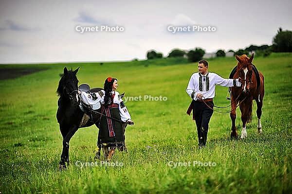 Young couple on national dress with horses [IBR123675136]