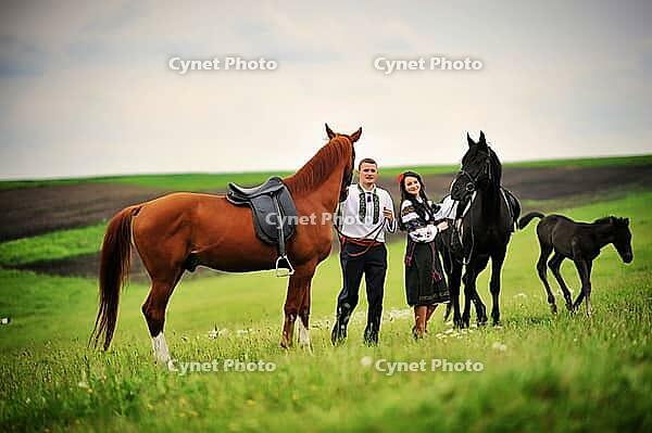 Young couple on national dress with horses [IBR123675140]