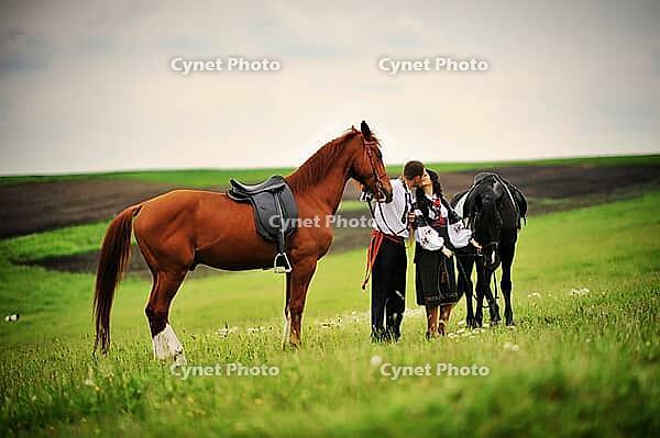 Young couple on national dress with horses [IBR123675143]