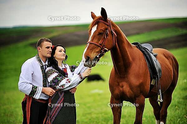 Young couple on national dress with horses [IBR123675158]