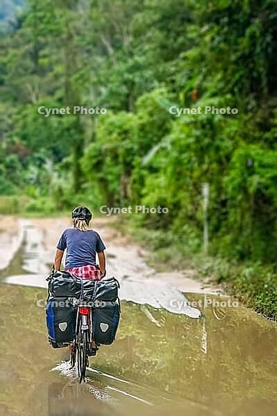 Female cyclist cycling on Trans-sumatran Highway in Sumatra, Indonesia [IBR123713395]