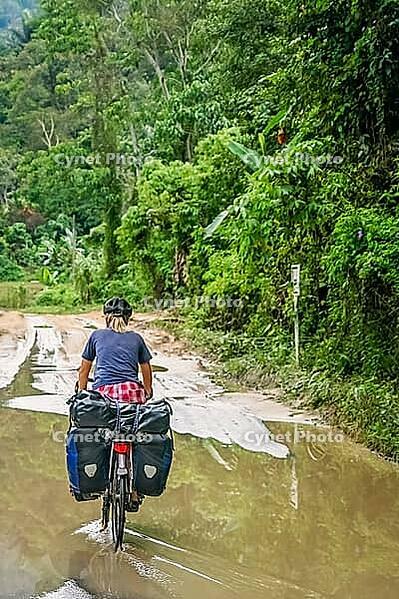 Female cyclist cycling on Trans-sumatran Highway in Sumatra, Indonesia [IBR123713396]