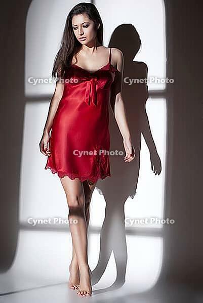 Fashion photo of beautiful woman in red nightdress in light of window [IBR123723152]