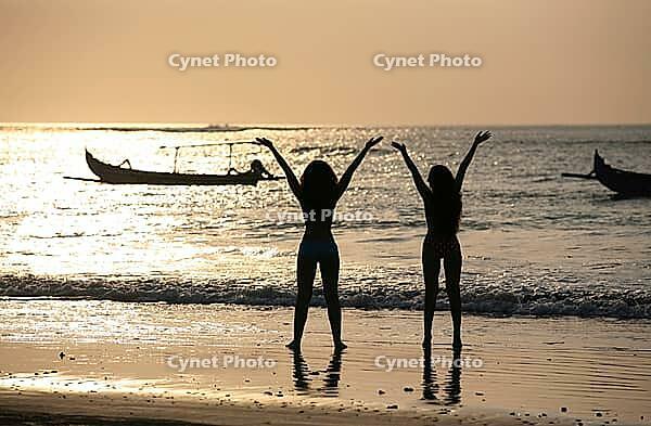 Two silhouettes of girls at coast of ocean [IBR123723216]