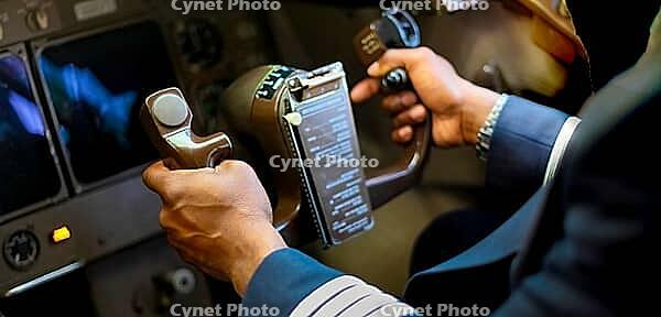 Cropped Hands of African Pilot flying a commercial airplane, cockpit view close up of hands [IBR123723294]