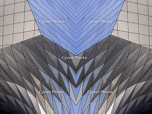 Abstract photography with a symmetrical, diamond-shaped shape that consists of repetitive lines and surfaces in shades of gray, white and blue and creates an impression of rhythm, depth and cool geometric harmony [IBR123760819]