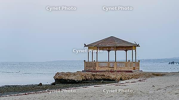 Wooden pavilion on a rock on a beach surrounded by the sea in peaceful twilight, Shoni Bay, Egypt [IBR123769629]
