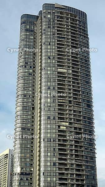 Elegant tall building with curved glass façade under a slightly cloudy sky, Singapore, Singapore [IBR123769656]