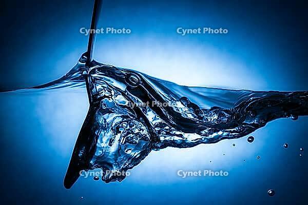 Spoon making waves in fresh water with blue background [IBR123878844]