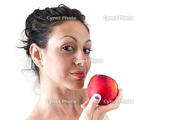 A girl while eating a peach, isolated on white background [IBR123878888]