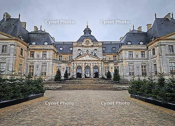 Maincy, France - December 11, 2025: Grand facade of Chateau de Vaux-le-Vicomte with cobblestone courtyard. Beautiful Baroque architecture decorated with small evergreen trees for the winter holidays [IBR123895601]