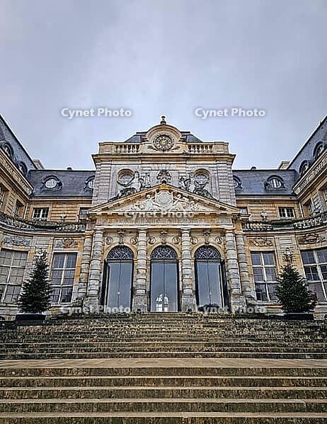 Maincy, France - December 11, 2025: Grand facade of Chateau de Vaux-le-Vicomte with cobblestone courtyard. Beautiful Baroque architecture decorated with small evergreen trees for the winter holidays [IBR123895603]