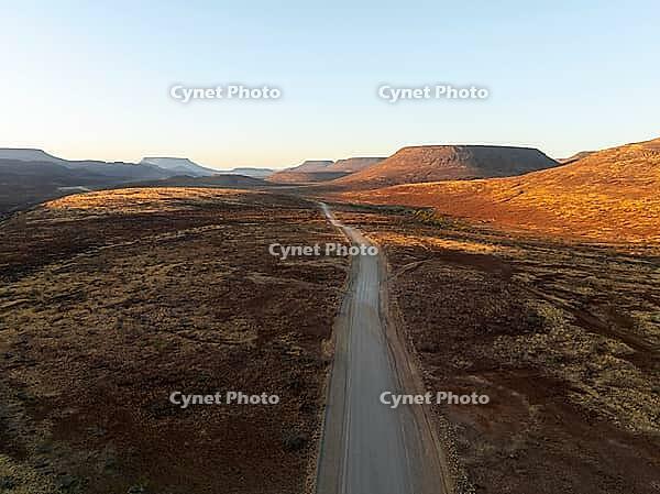 Aerial view, infinite space, straight road leads through dry desert landscape, hills in Damaraland, Namibia [IBR123990977]