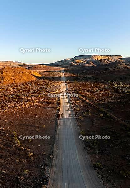 Aerial view, infinite space, straight road leads through dry desert landscape, hills in Damaraland, Namibia [IBR123990980]