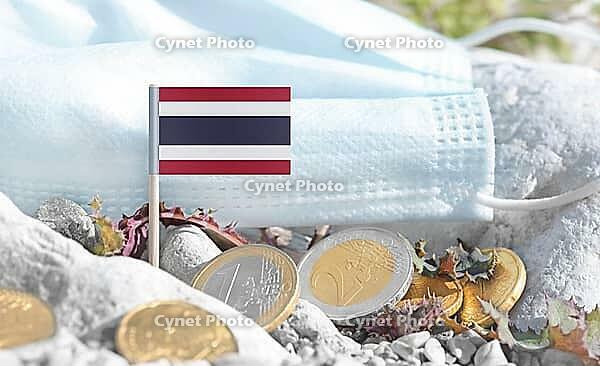Thai flag with euro currency coins and a medical mask on rocky ground.International healthcare costs, medical funding, Europe and Thailand cooperation and global health finance [IBR124084105]