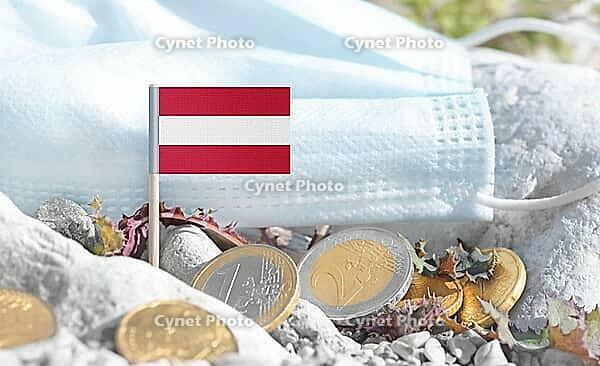 Austrian flag with euro currency coins and a medical mask on rocky ground.Eurozone healthcare costs, medical funding challenges and the financial weight of modern services connected to Austria [IBR124084111]