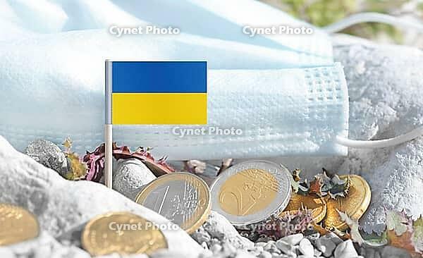 Ukrainian flag with euro currency coins and a medical mask on rocky ground.International healthcare costs, medical funding, Europe and Ukraine cooperation and global health finance [IBR124084112]