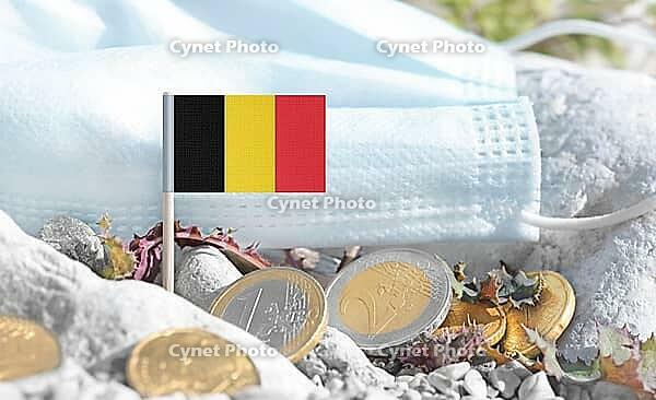 Belgium flag with euro currency coins and a medical mask on rocky ground.Eurozone healthcare costs, medical funding challenges and the financial weight of modern services connected to Belgium [IBR124084113]