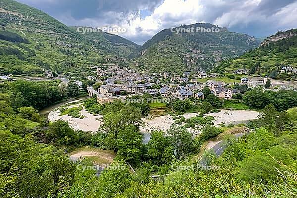 Village in a river valley under dramatic skies and mountains, Gorges du Tarn Causses, Occitania, France [IBR124084168]