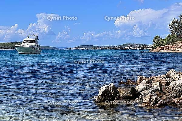 Rocky beach with clear water and boat, Rab, Lika-Senj County, Croatia [IBR124084173]