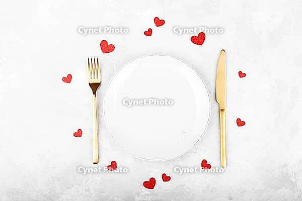 Romantic table setting with golden cutlery on white stone table.Valentine's day card template [IBR124084179]
