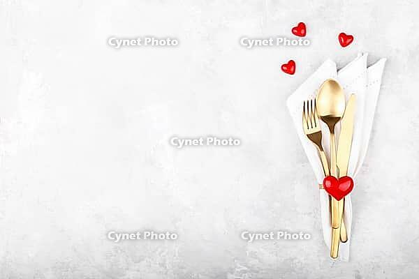 Romantic table setting with golden cutlery on white stone table.Valentine's day card template [IBR124084181]