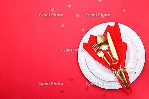 Romantic table setting, gold cutlery on the red table cloth. Valentine's day celebration [IBR124084183]
