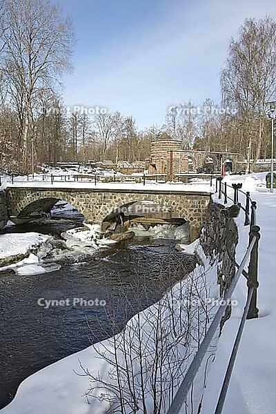 The ruins of the historic Borgvik Ironworks. Industrial stone architecture on a river in winter with snow and blue skies. Cultural heritage site in picturesque countryside in Värmland, Sweden [IBR124200517]
