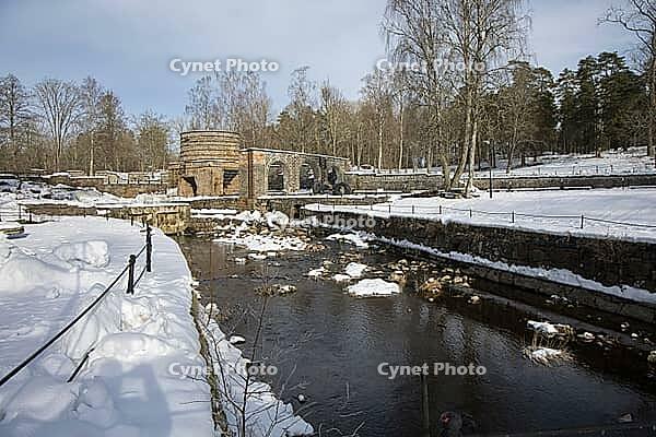 The ruins of the historic Borgvik Ironworks. Industrial stone architecture on a river in winter with snow and blue skies. Cultural heritage site in picturesque countryside in Värmland, Sweden [IBR124200518]