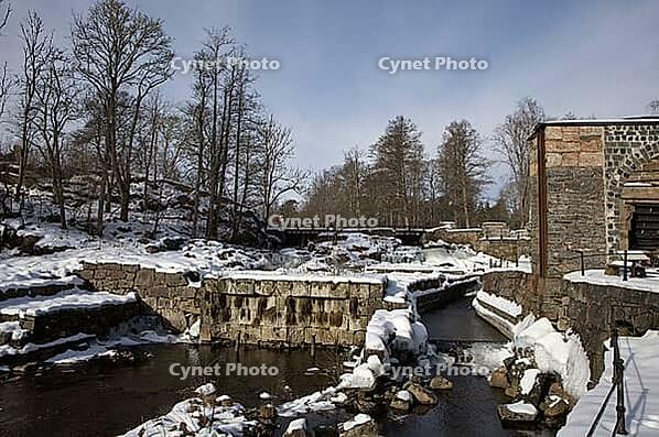 The ruins of the historic Borgvik Ironworks. Industrial stone architecture on a river in winter with snow and blue skies. Cultural heritage site in picturesque countryside in Värmland, Sweden [IBR124200520]