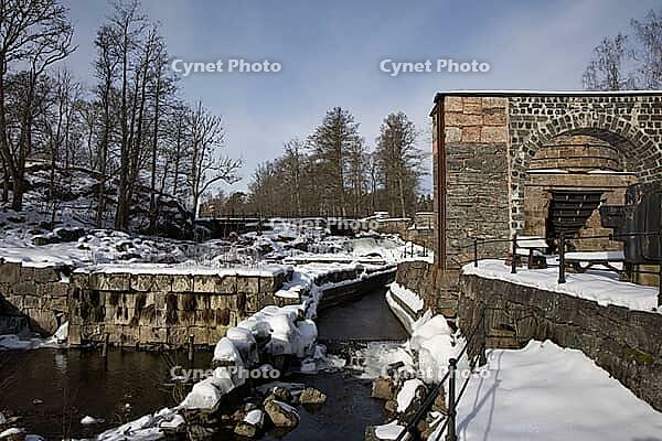 The ruins of the historic Borgvik Ironworks. Industrial stone architecture on a river in winter with snow and blue skies. Cultural heritage site in picturesque countryside in Värmland, Sweden [IBR124200522]