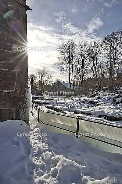 The ruins of the historic Borgvik Ironworks. Industrial stone architecture on a river in winter with snow and blue skies. Cultural heritage site in picturesque countryside in Värmland, Sweden [IBR124200527]