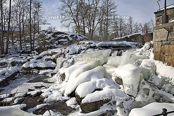 The ruins of the historic Borgvik Ironworks. Industrial stone architecture on a river in winter with snow and blue skies. Cultural heritage site in picturesque countryside in Värmland, Sweden [IBR124200528]
