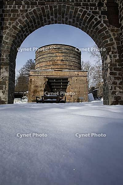 The ruins of the historic Borgvik Ironworks. Industrial stone architecture on a river in winter with snow and blue skies. Cultural heritage site in picturesque countryside in Värmland, Sweden [IBR124200531]