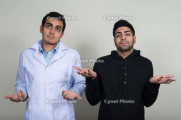 Studio shot of two young Indian men as doctor and patient together against white background [IBR124308998]