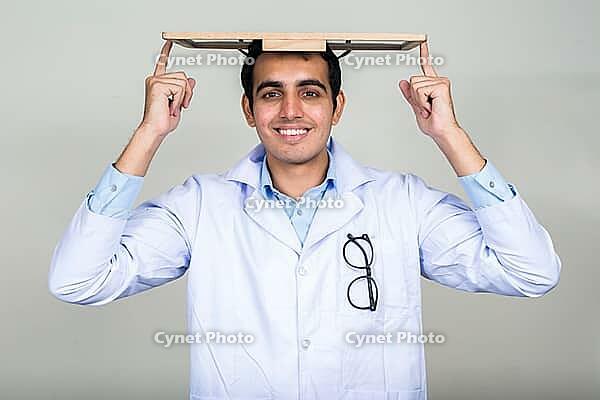Studio shot of young handsome Indian man doctor against white background [IBR124309001]