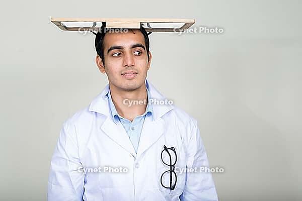 Studio shot of young handsome Indian man doctor against white background [IBR124309007]