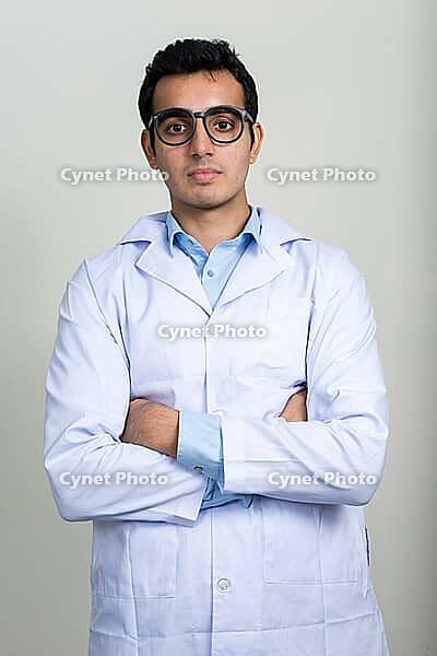 Studio shot of young handsome Indian man doctor against white background [IBR124309009]