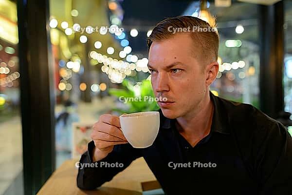 Portrait of young handsome Scandinavian businessman relaxing at the coffee shop [IBR124309024]