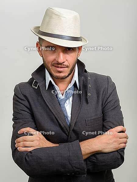 Studio shot of handsome bearded Hispanic businessman wearing hat against white background [IBR124309038]