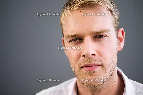 Portrait of young handsome man with blond hair against gray background [IBR124309043]