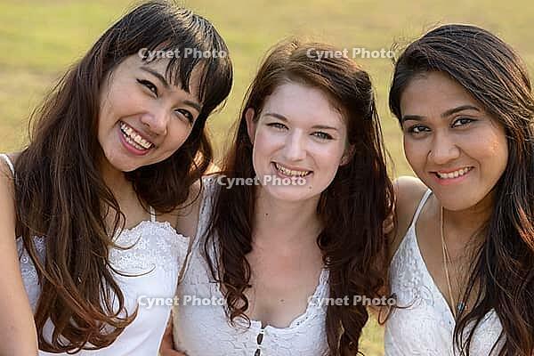 Portrait of three multi ethnic young beautiful women as friends together at the park outdoors [IBR124309044]