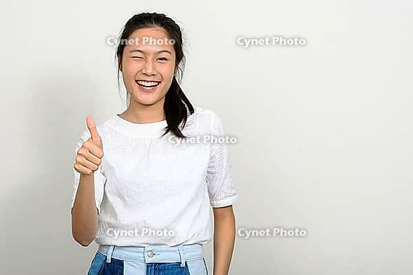 Studio shot of young beautiful Asian teenage girl against white background [IBR124309049]