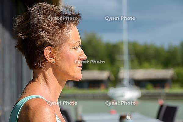 Portrait of mature beautiful woman with short hair at restaurant by the pier outdoors [IBR124309050]