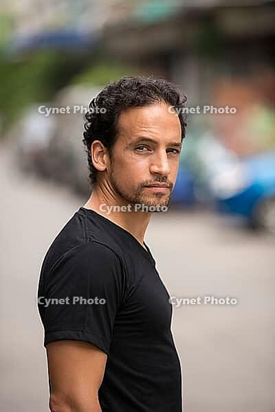 Portrait of handsome bearded Hispanic man with curly hair in the streets outdoors [IBR124309057]